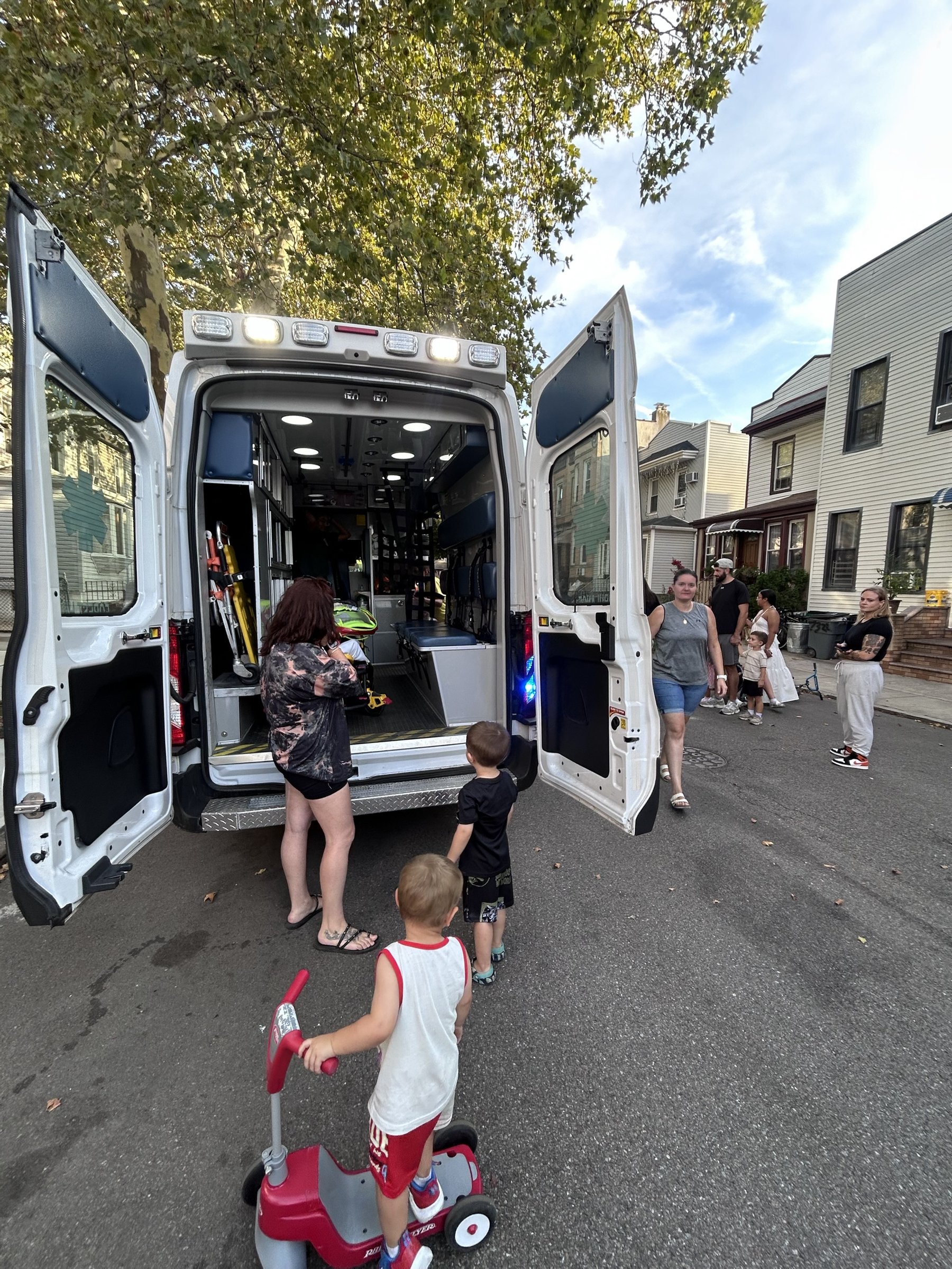 The rear doors of ambulance FH4 standing open on the street, with two small children watching from behind