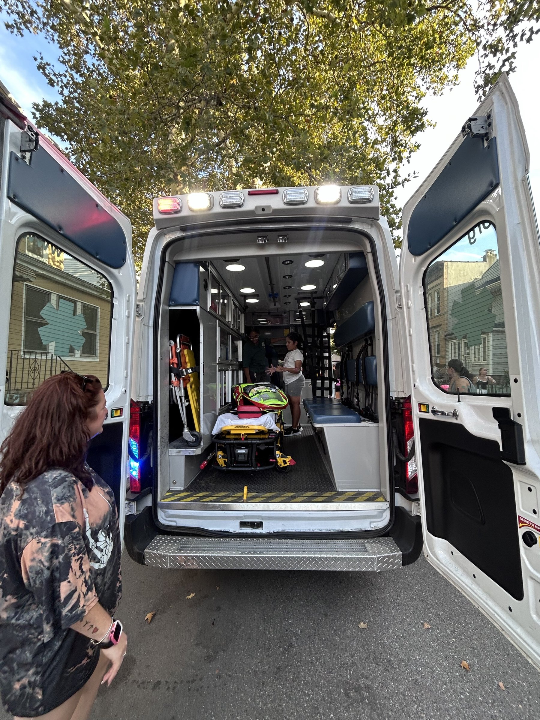 An FHVAC crew member in uniform showing a young visitor around the inside of the ambulance, stretcher and equipment visible