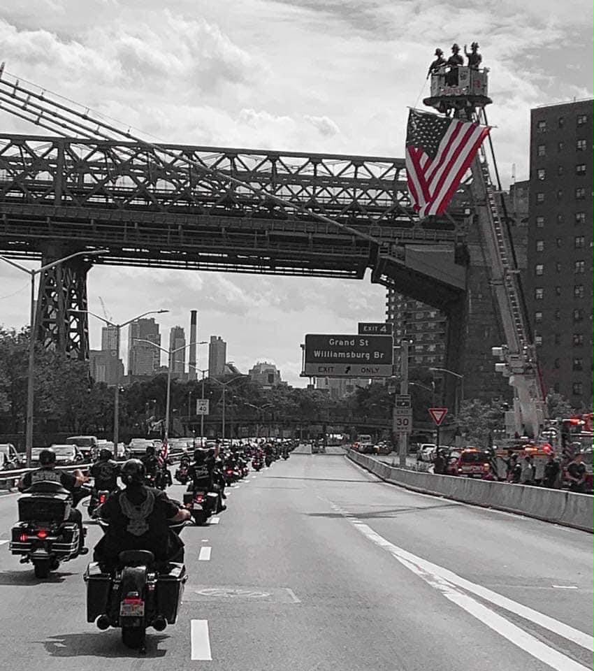 Riders pass beneath an FDNY ladder truck flying the flag